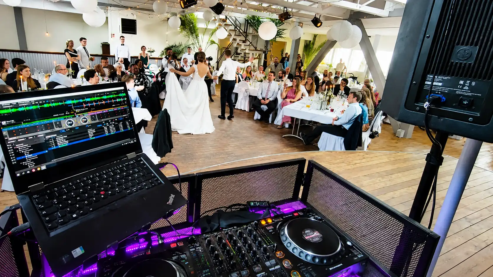 Blick vom DJ-Pult auf das Brautpaar beim Tanz in einem hellen Hochzeitssaal