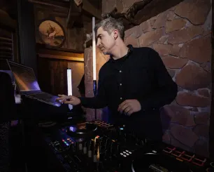 DJ Beatgee am DJ-Pult vor einer Natursteinwand