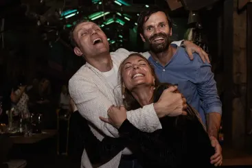 Drei Freunde lachen und umarmen sich auf der Party
