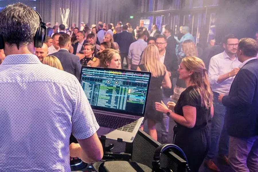 Blick über die Schulter von DJ Beatgee auf eine Firmenfeier im vollen Saal
